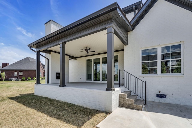 exterior space with brick siding, a ceiling fan, a lawn, crawl space, and a patio area