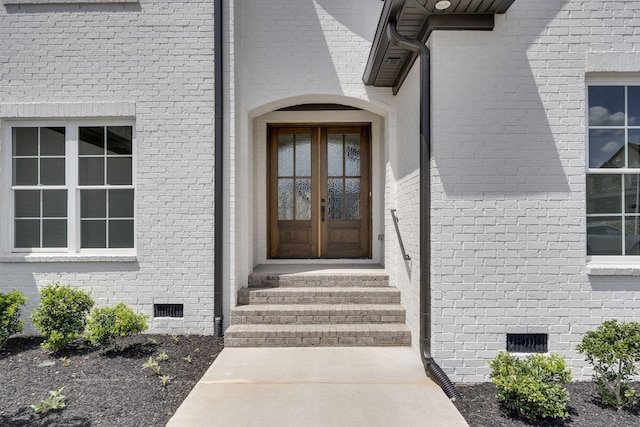 entrance to property featuring crawl space, brick siding, and french doors