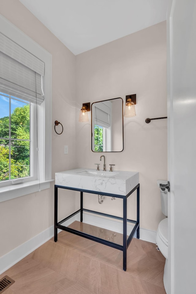 bathroom with toilet, vanity, visible vents, and baseboards