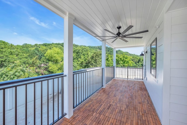 view of patio / terrace with ceiling fan, a balcony, and a view of trees