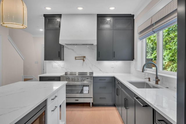 kitchen with custom range hood, appliances with stainless steel finishes, a sink, gray cabinetry, and backsplash