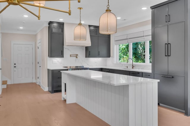 kitchen with a center island, crown molding, light wood finished floors, gray cabinets, and decorative backsplash