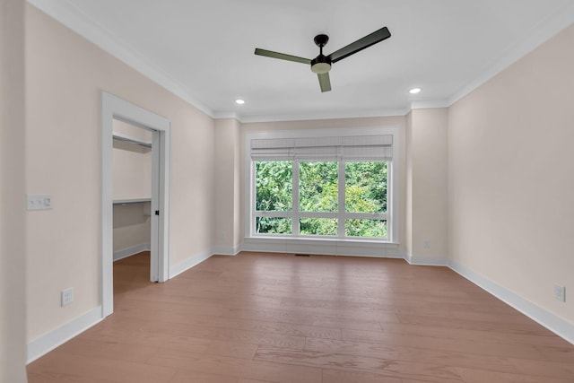 unfurnished room with ornamental molding, wood finished floors, a ceiling fan, and baseboards