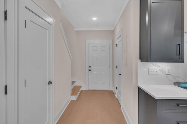 interior space with light wood-style flooring, visible vents, baseboards, stairs, and ornamental molding