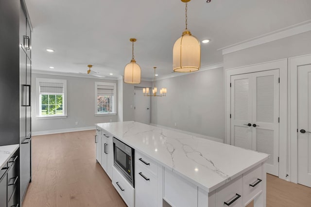 kitchen with light wood-style flooring, stainless steel microwave, crown molding, pendant lighting, and recessed lighting