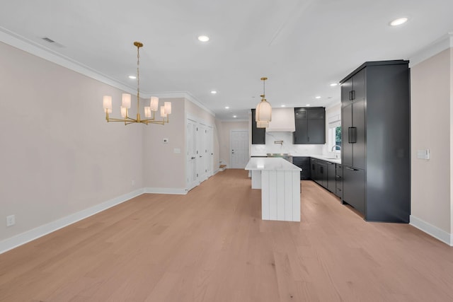 kitchen featuring baseboards, light countertops, a center island, light wood finished floors, and crown molding