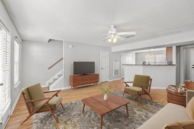 living room with light wood-style floors, stairway, visible vents, and a ceiling fan