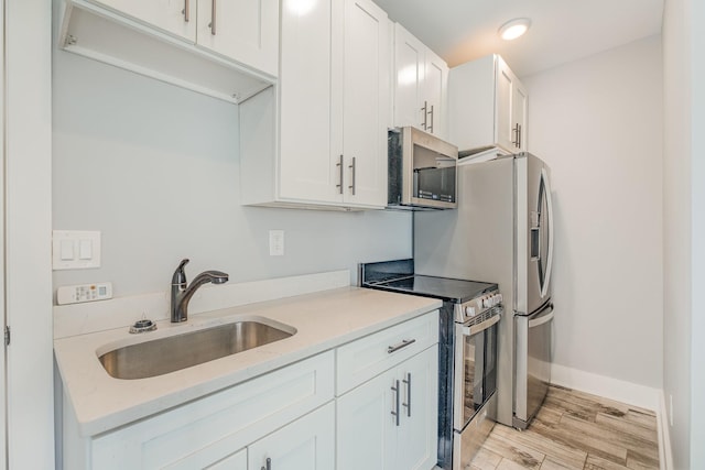 64 Harbor Pt, Lebanon, TN 37087 - kitchen with appliances with stainless steel finishes, a sink, light wood finished floors, white cabinets, and baseboards