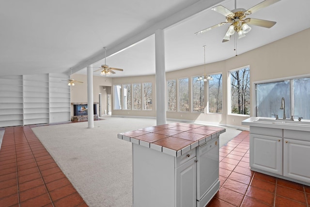 kitchen with tile countertops, white dishwasher, a sink, and white cabinetry