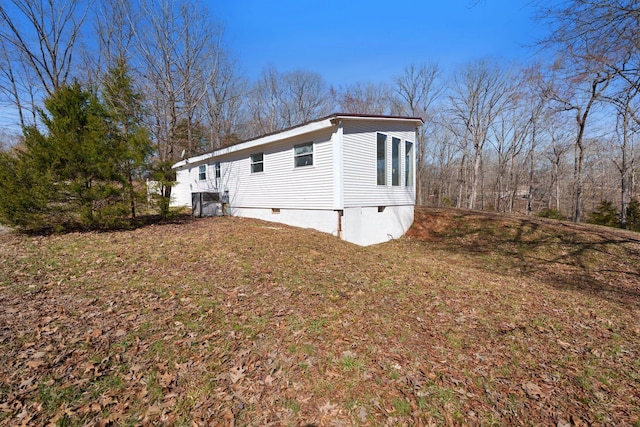 view of side of home with crawl space and a yard