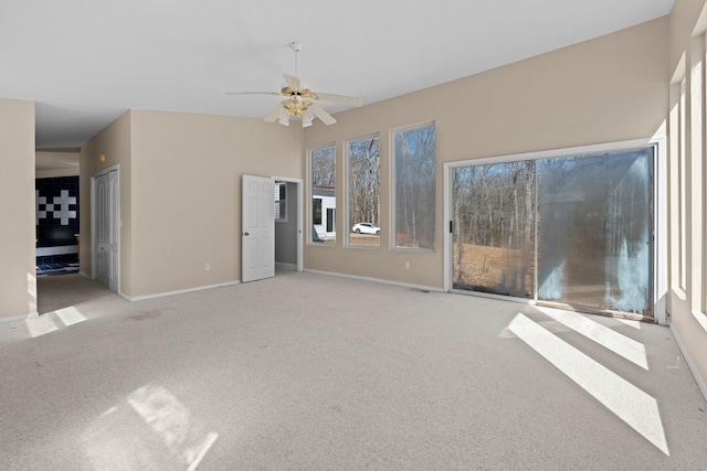 unfurnished living room with carpet floors, baseboards, and a ceiling fan