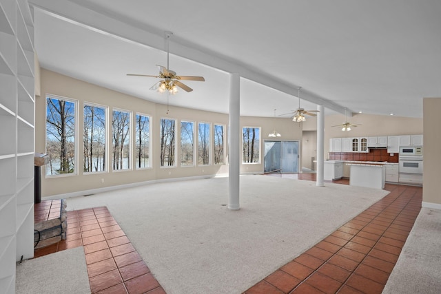 unfurnished living room with vaulted ceiling with beams, light tile patterned floors, light carpet, ceiling fan, and baseboards