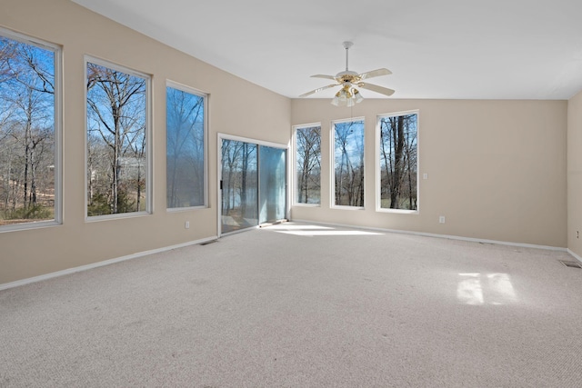 carpeted empty room with ceiling fan, visible vents, baseboards, and a wealth of natural light