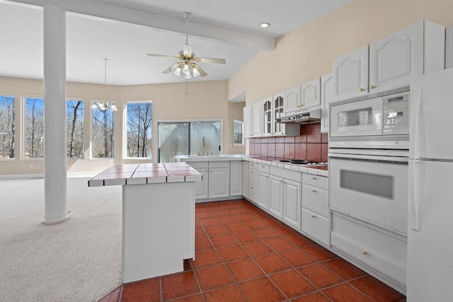 kitchen with white appliances, tile counters, decorative backsplash, under cabinet range hood, and beam ceiling