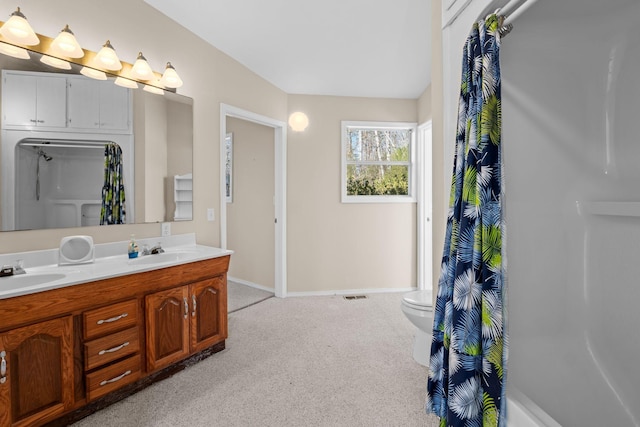 full bath with double vanity, carpet, a sink, and baseboards