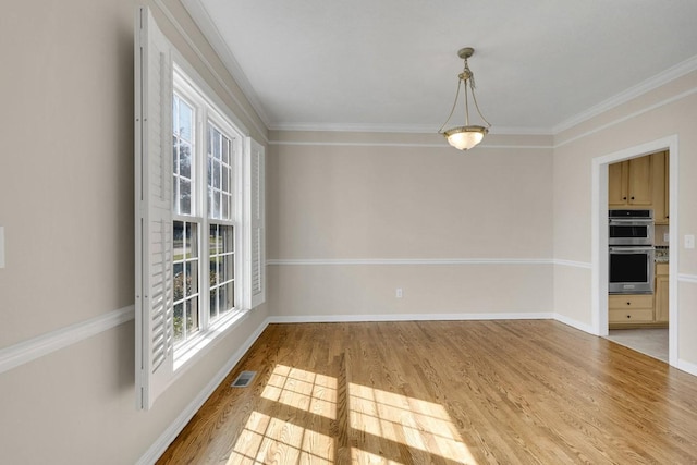 spare room featuring ornamental molding, wood finished floors, visible vents, and baseboards