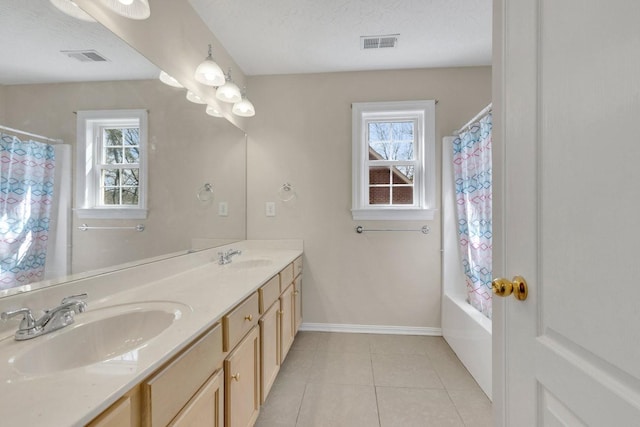 bathroom featuring a healthy amount of sunlight, visible vents, a sink, and tile patterned floors