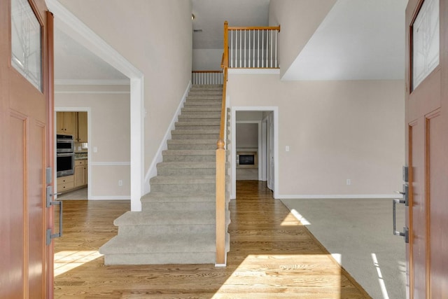 entrance foyer featuring stairs, baseboards, a high ceiling, and wood finished floors