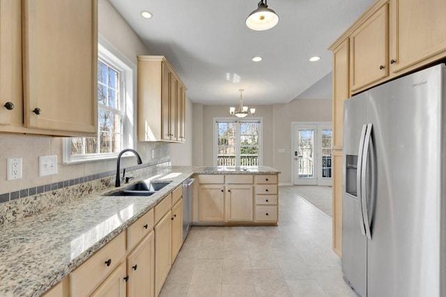 kitchen with light brown cabinetry, appliances with stainless steel finishes, a peninsula, and a sink