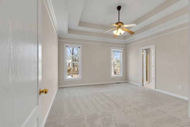 spare room featuring ceiling fan, carpet flooring, baseboards, ornamental molding, and a raised ceiling