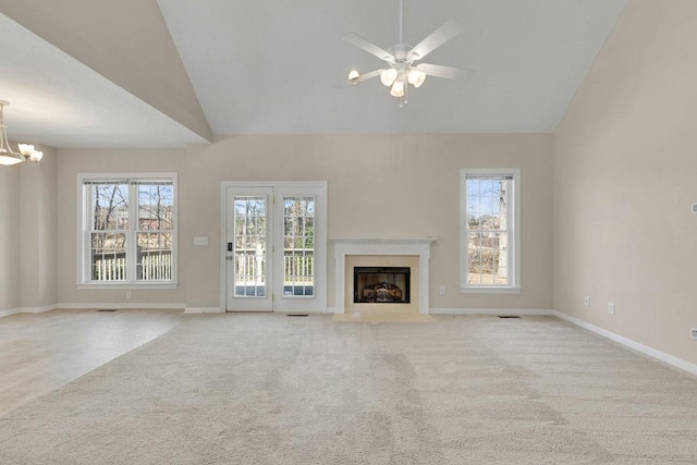 unfurnished living room with ceiling fan with notable chandelier, carpet, a fireplace with flush hearth, and baseboards