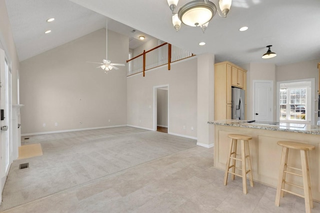 kitchen featuring light colored carpet, visible vents, light brown cabinets, stainless steel fridge, and baseboards