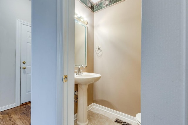 bathroom featuring toilet, wood finished floors, visible vents, and baseboards