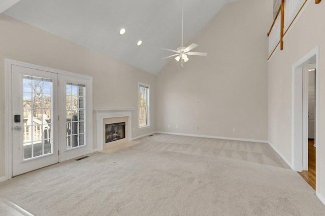 unfurnished living room featuring high vaulted ceiling, a fireplace with flush hearth, carpet flooring, visible vents, and baseboards