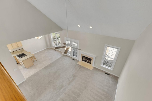 unfurnished living room with lofted ceiling, a premium fireplace, carpet, and visible vents