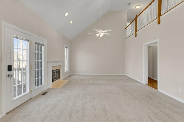 unfurnished living room with carpet floors, a premium fireplace, high vaulted ceiling, and baseboards