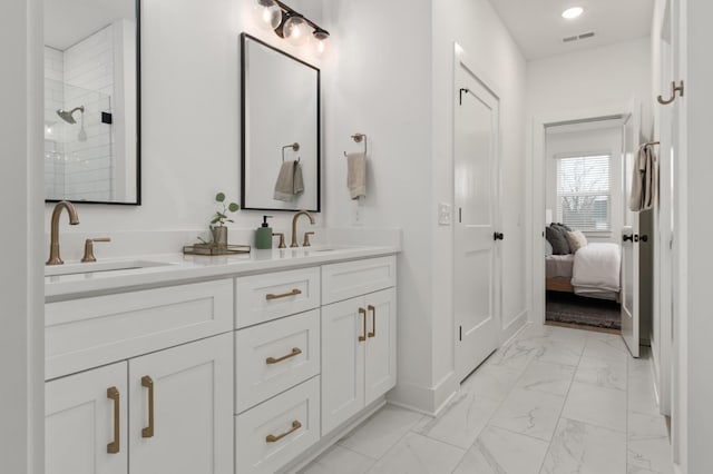 full bathroom featuring marble finish floor, a sink, a tile shower, and double vanity