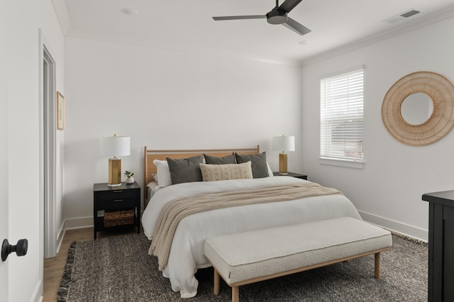 bedroom featuring baseboards, visible vents, crown molding, and wood finished floors