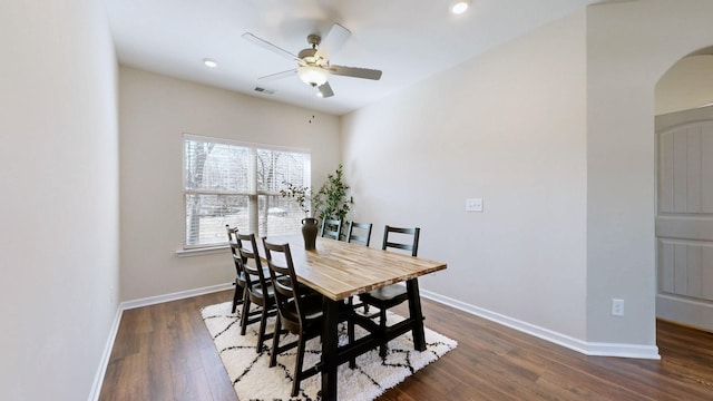 dining space featuring arched walkways, visible vents, dark wood-type flooring, ceiling fan, and baseboards