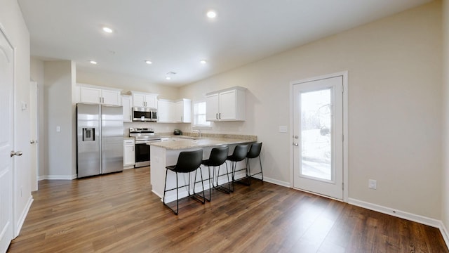 kitchen featuring appliances with stainless steel finishes, dark wood-type flooring, a peninsula, and a kitchen breakfast bar