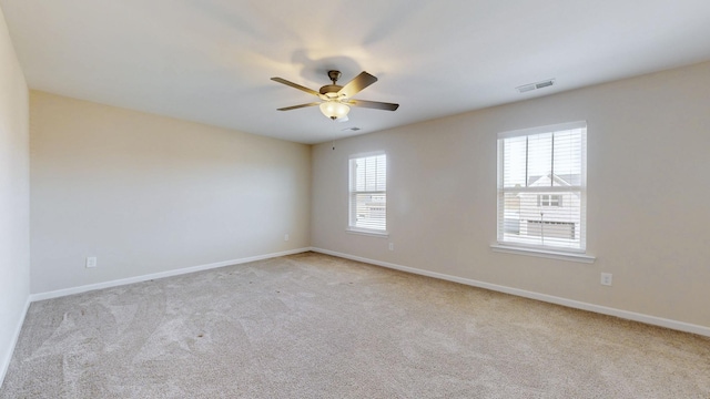 carpeted spare room with ceiling fan, visible vents, and baseboards