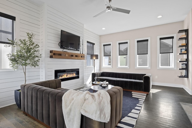 living room featuring a large fireplace, baseboards, ceiling fan, dark wood-type flooring, and recessed lighting