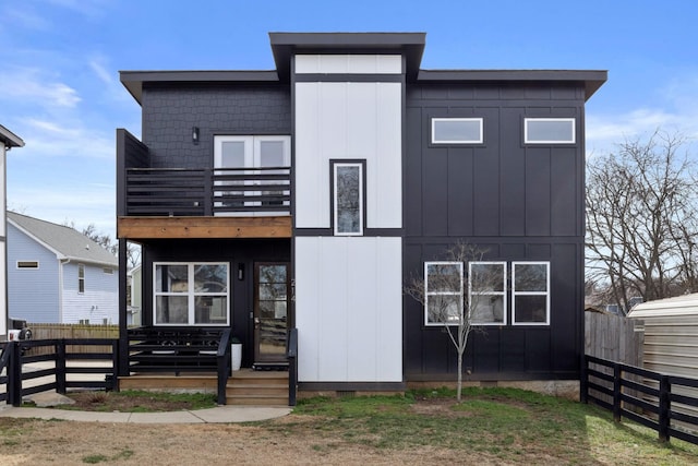 view of front of home featuring board and batten siding, fence private yard, and a balcony