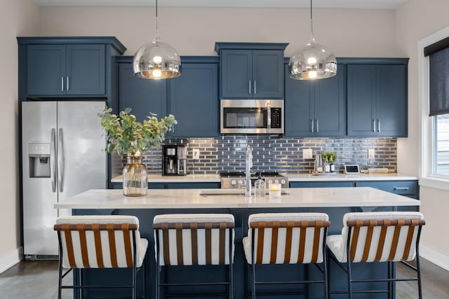 kitchen featuring blue cabinets, tasteful backsplash, a center island with sink, and appliances with stainless steel finishes