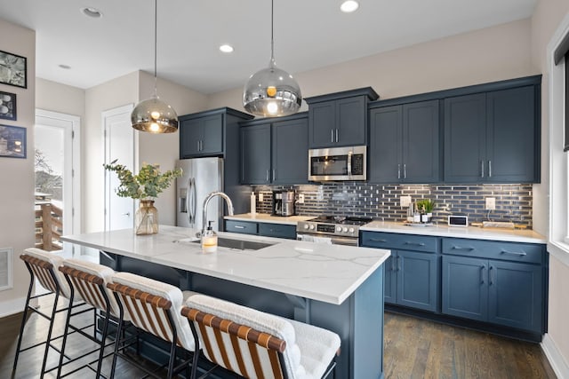 kitchen with stainless steel appliances, a breakfast bar, an island with sink, and a sink