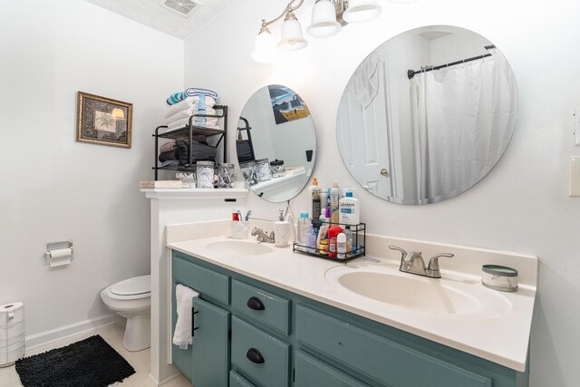 bathroom with double vanity, toilet, visible vents, and a sink