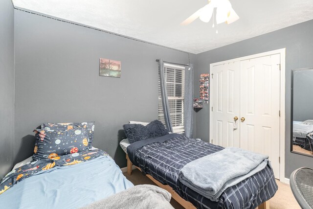 carpeted bedroom featuring baseboards, a closet, and ceiling fan