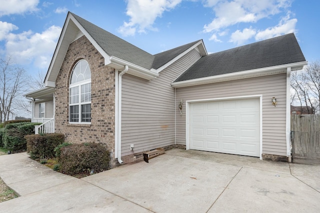 view of side of home with brick siding, fence, roof with shingles, driveway, and an attached garage