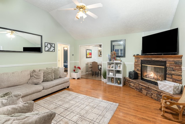 living room with wood finished floors, high vaulted ceiling, ceiling fan, and a fireplace