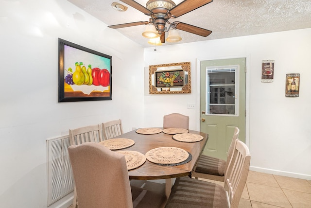 dining room featuring light tile patterned flooring, baseboards, a textured ceiling, and a ceiling fan