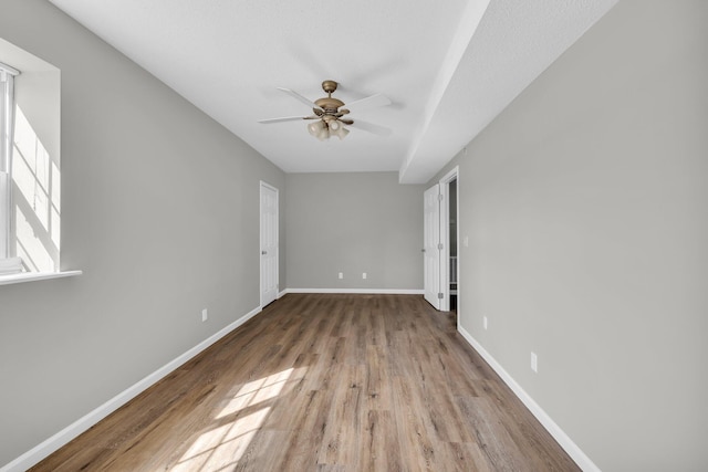 interior space featuring ceiling fan, baseboards, and wood finished floors