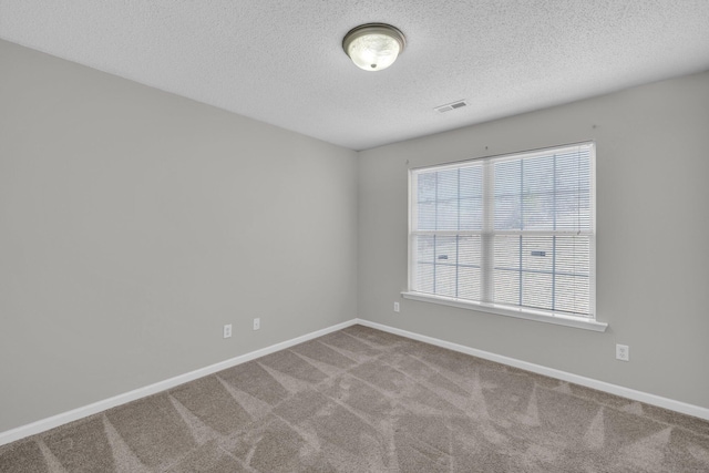 empty room featuring carpet floors, baseboards, visible vents, and a textured ceiling