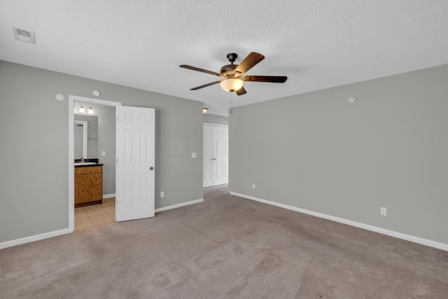 unfurnished bedroom with light carpet, a textured ceiling, visible vents, and baseboards