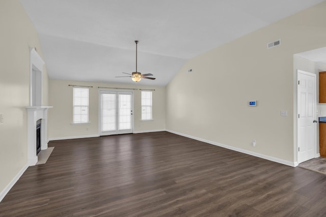 unfurnished living room with visible vents, dark wood finished floors, a ceiling fan, a fireplace with flush hearth, and vaulted ceiling