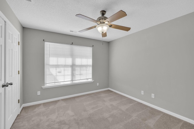 unfurnished room featuring carpet, visible vents, a textured ceiling, and baseboards