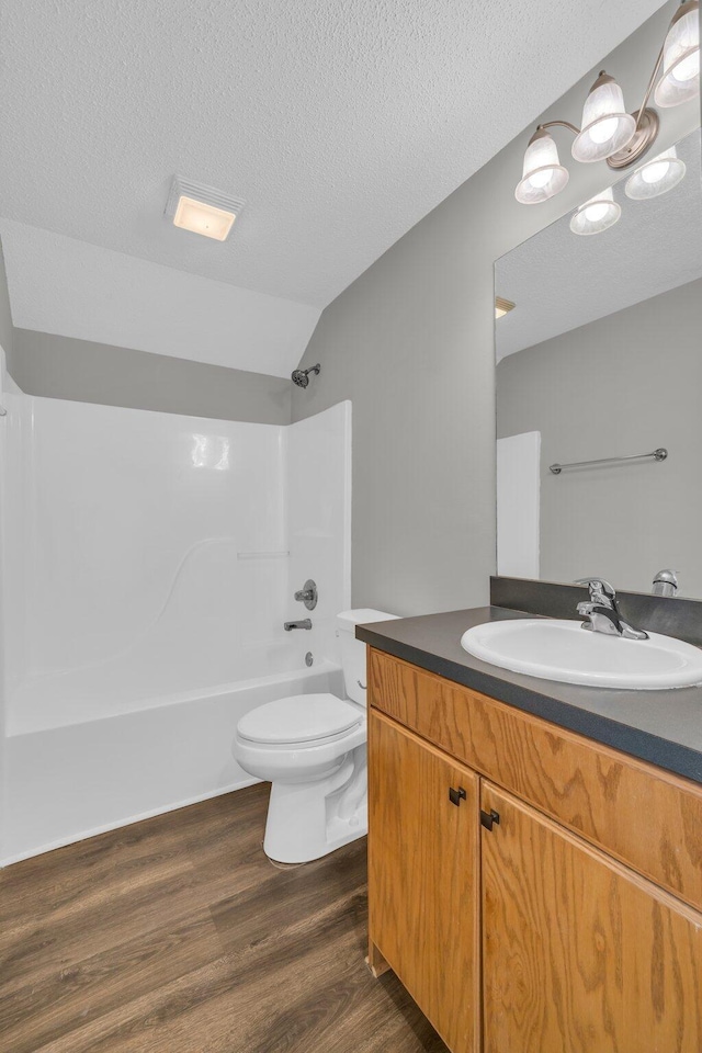 bathroom featuring lofted ceiling, toilet, wood finished floors, vanity, and  shower combination